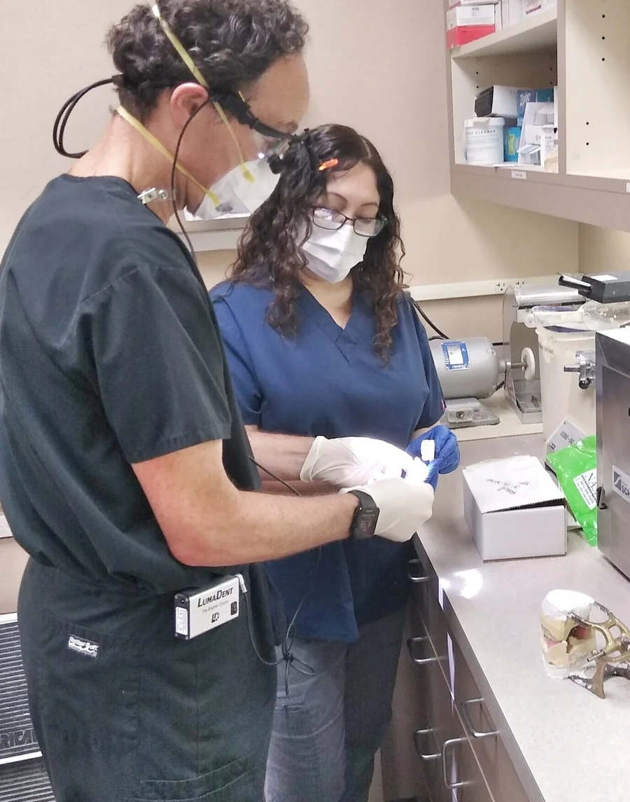Dr. William Neff, in a mask and loupes, preparing for a dental case with an assistant.
