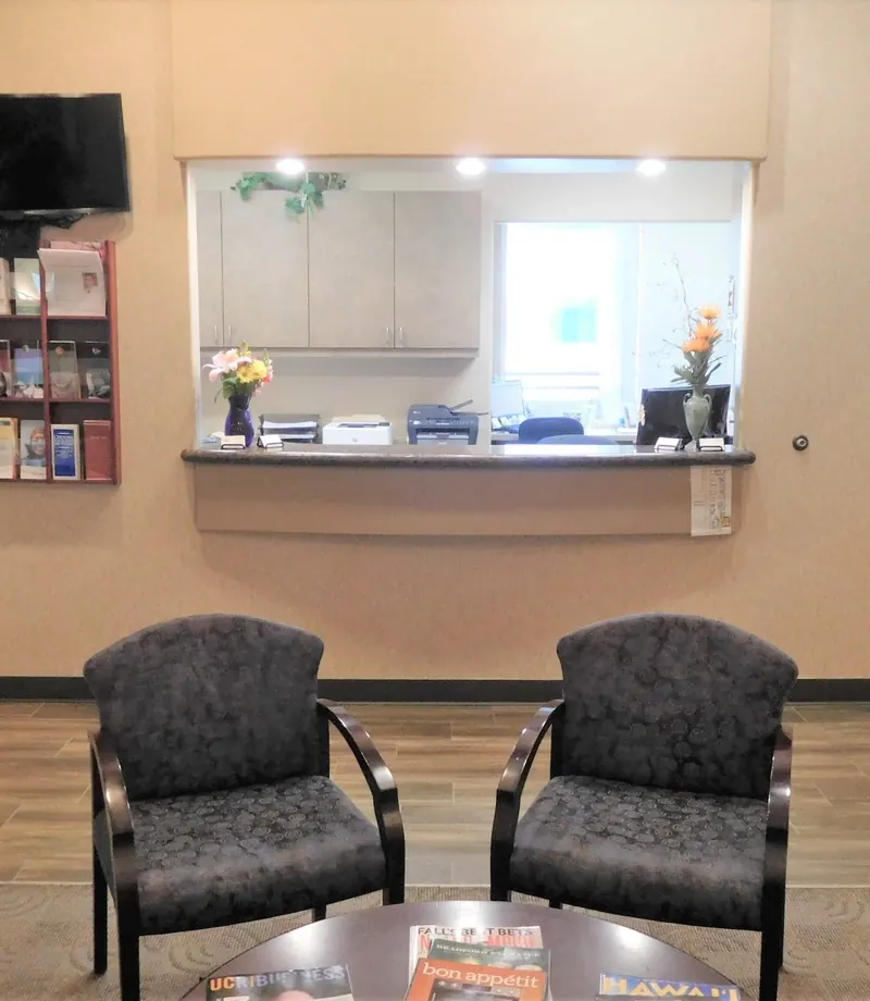 The reception desk window, with a television on the wall beside it.